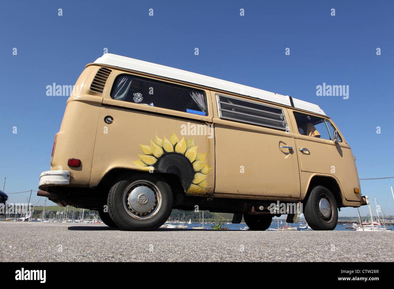 Beige Volkswagon VW Campingbus mit Sonnenblumen Gemälde auf Seite geparkt am Kai in Falmouth, Cornwall, UK Stockfoto