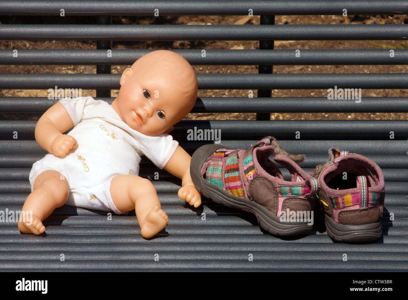 Ein Kunststoff Babypuppe sitzt neben Babyschuhen auf Metallbank in Georgetown Waterfront Park, Washington, DC Stockfoto