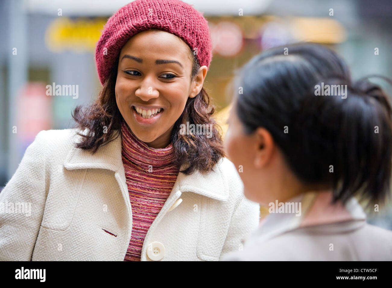 Zwei weibliche Geschäftspartnern haben eine beiläufige Diskussion in der Stadt mit einem Lächeln auf ihren Gesichtern. Geringe Schärfentiefe. Stockfoto