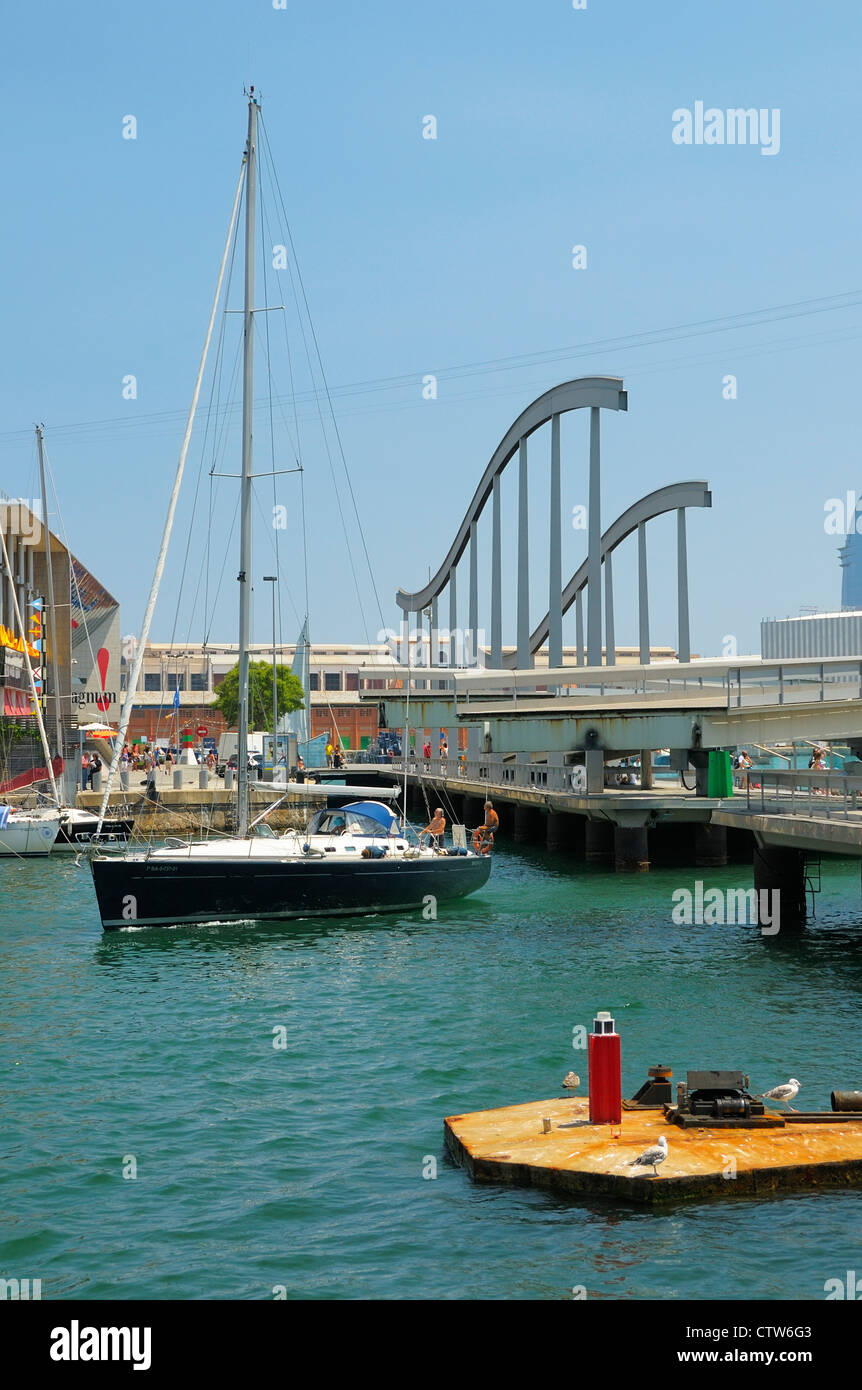 Ein Segelboot betreten der Marina durch die Drehung Fußgängerbrücke an der Rambla del Mar in Port Vell, Barcelona, Spanien Stockfoto