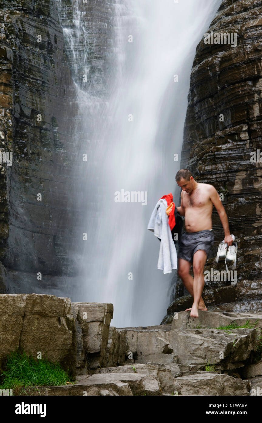 Ein Mann im Badeanzug vor einem Wasserfall Stockfoto