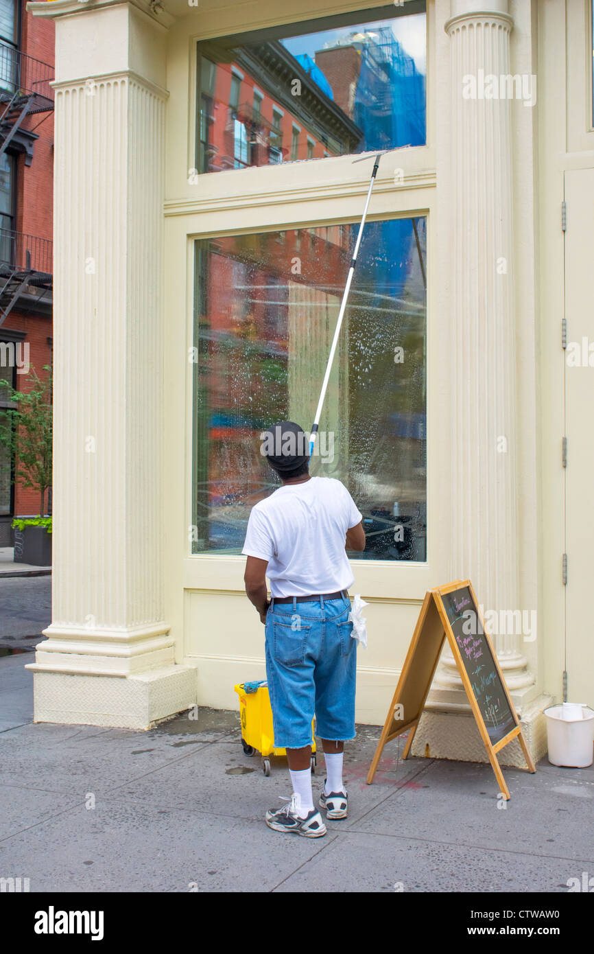 Fensterputzer reinigt ein Fenster von einem Soho Geschäft in New York City Stockfoto
