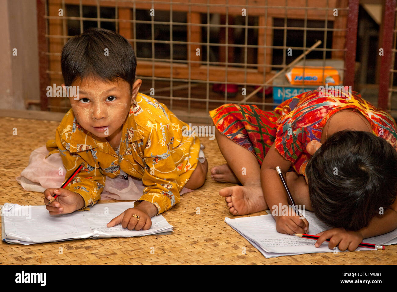 Myanmar, Burma. Bagan. Junge burmesische Mädchen schreiben in ihre Hefte. Thanaka einfügen, einen kosmetischen Sonnenschutz im Gesicht hat. Stockfoto