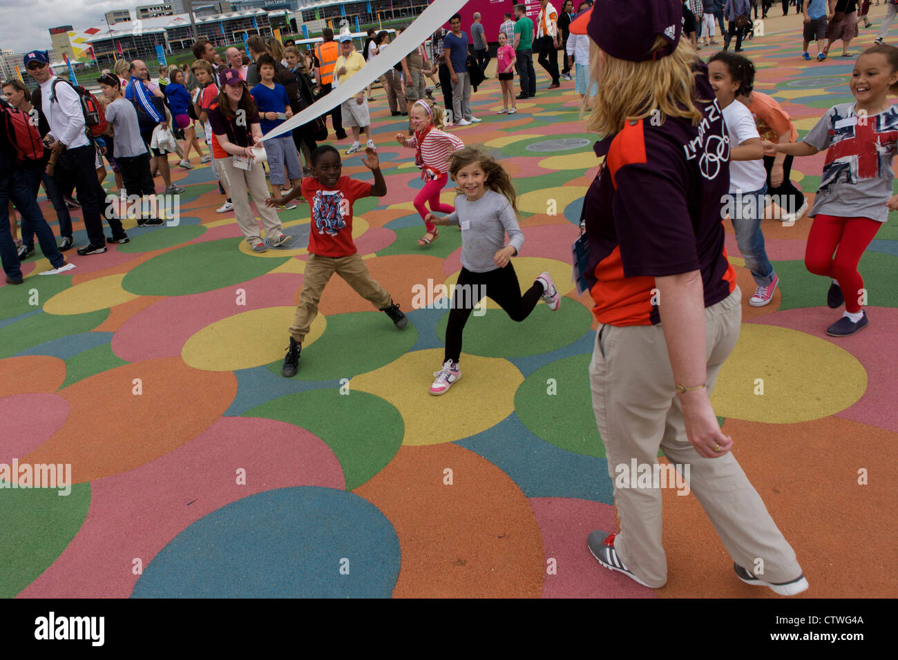 Kinder-Praxis eine Sprint-Finale auf dem gitterartigen gemusterte Boden im Olympiapark während der Olympischen Spiele 2012 in London zu gewinnen. Das Kinderrennen am Vortag unter ein vorgeben Spur-Tonband, gehalten von zwei freiwilligen Spiele-Hersteller, die "jeder" Schokolade Goldmedaillen Gewinner anbieten. Stockfoto