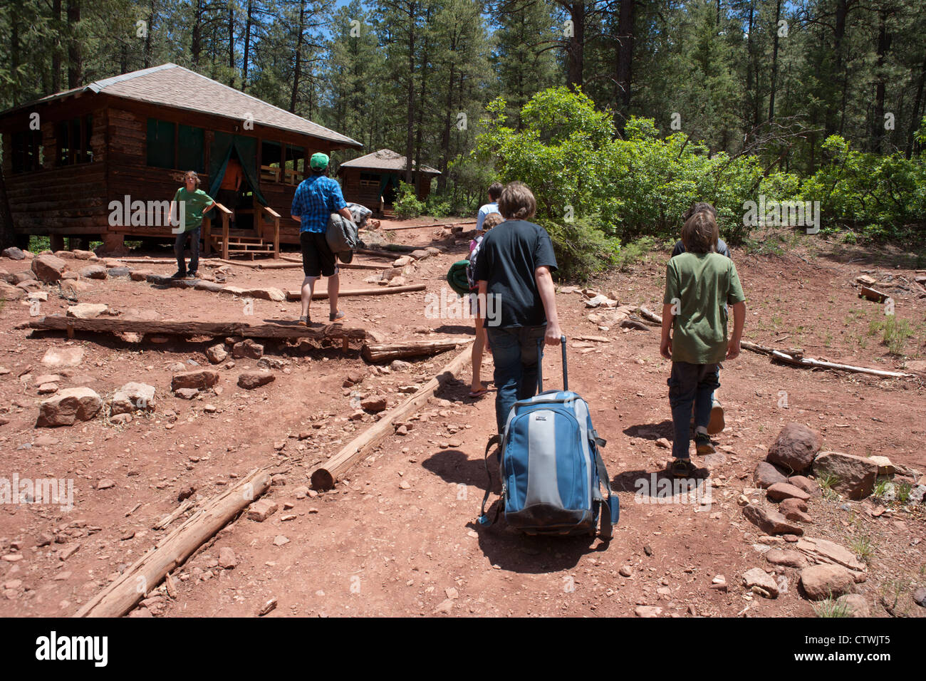 10 - 13 Jahre alten Jungen mit Gepäck zu Fuß zu ihren Kabinen zu Beginn der Sommer-Camp, Südwesten der USA. Stockfoto