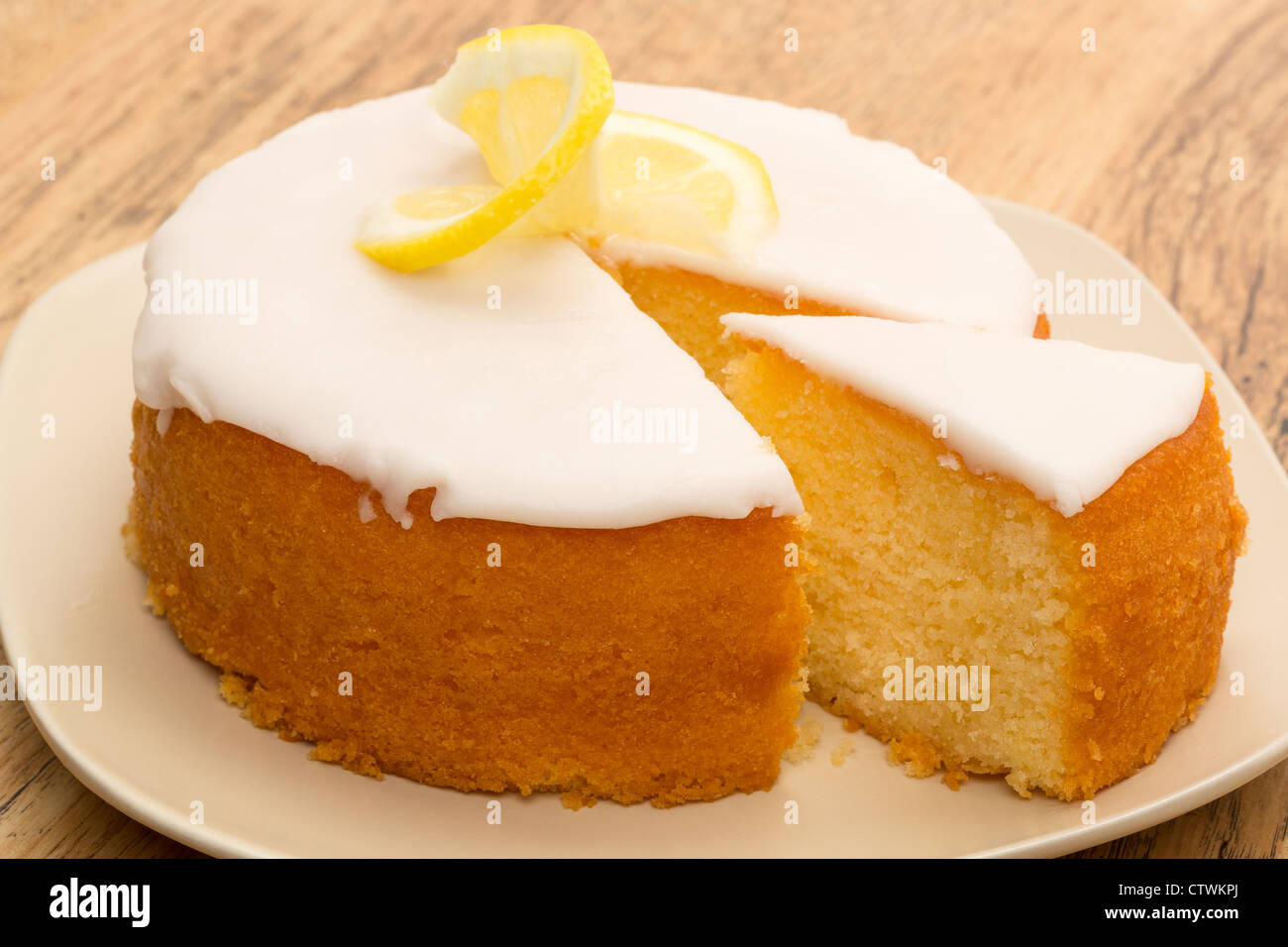 Eine ganze Zitrone beträufeln Kuchen mit einem Stück herausgenommen. Stockfoto