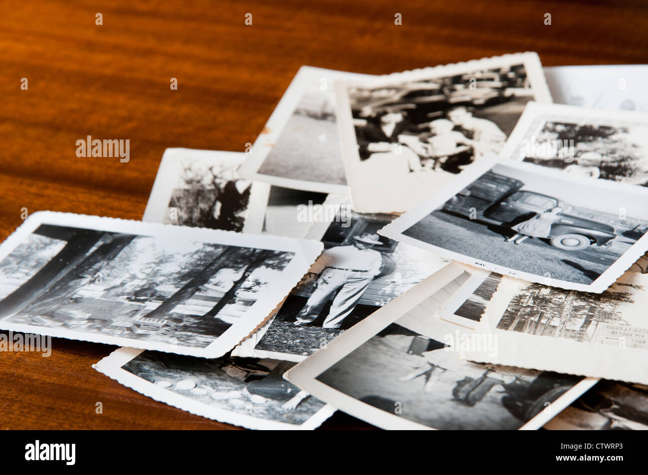 Haufen alter schwarz-weiß Familienfotos auf einem Tisch Stockfoto
