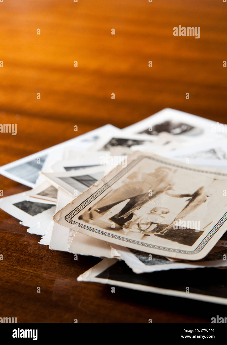 Haufen alter schwarz-weiß Familienfotos auf einem Tisch Stockfoto