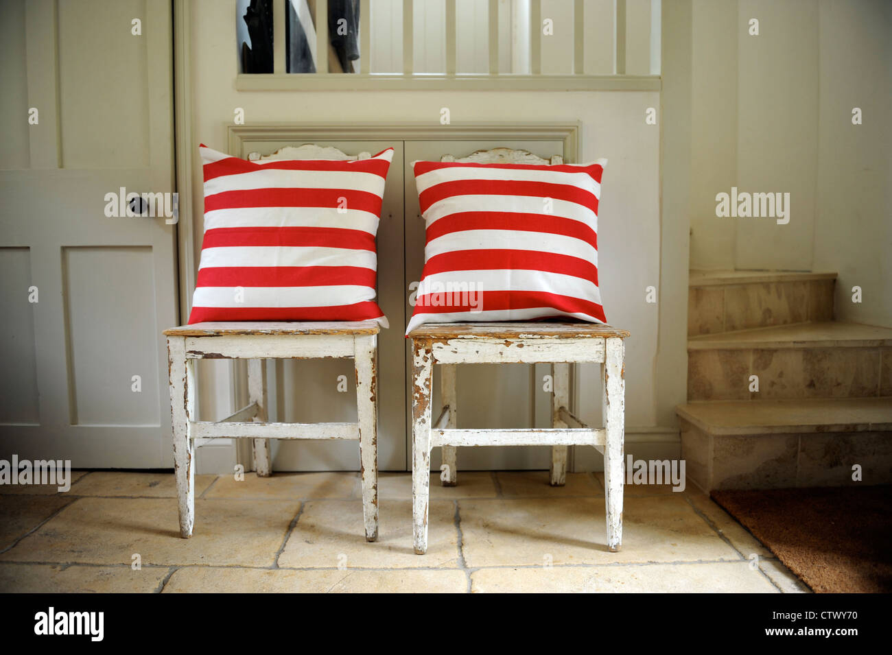 Alten distressed Holzstühle mit modernen rot-weiß gestreiften Kissen UK Stockfoto