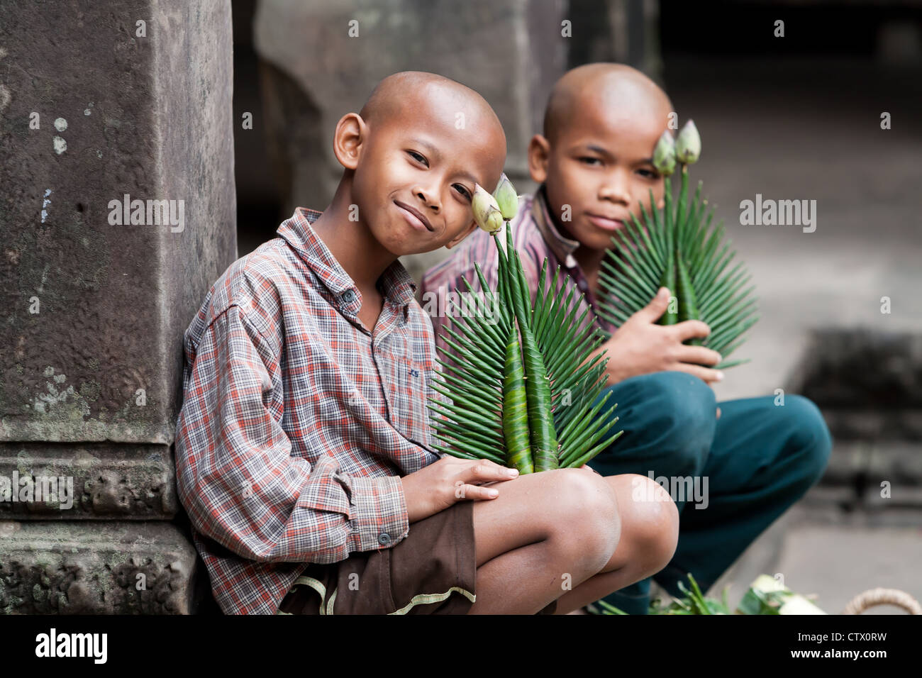 Junge buddhistische Jungs verkaufen Blumen an Touristen innerhalb der Tempelanlage Angkor Wat Komplex Stockfoto