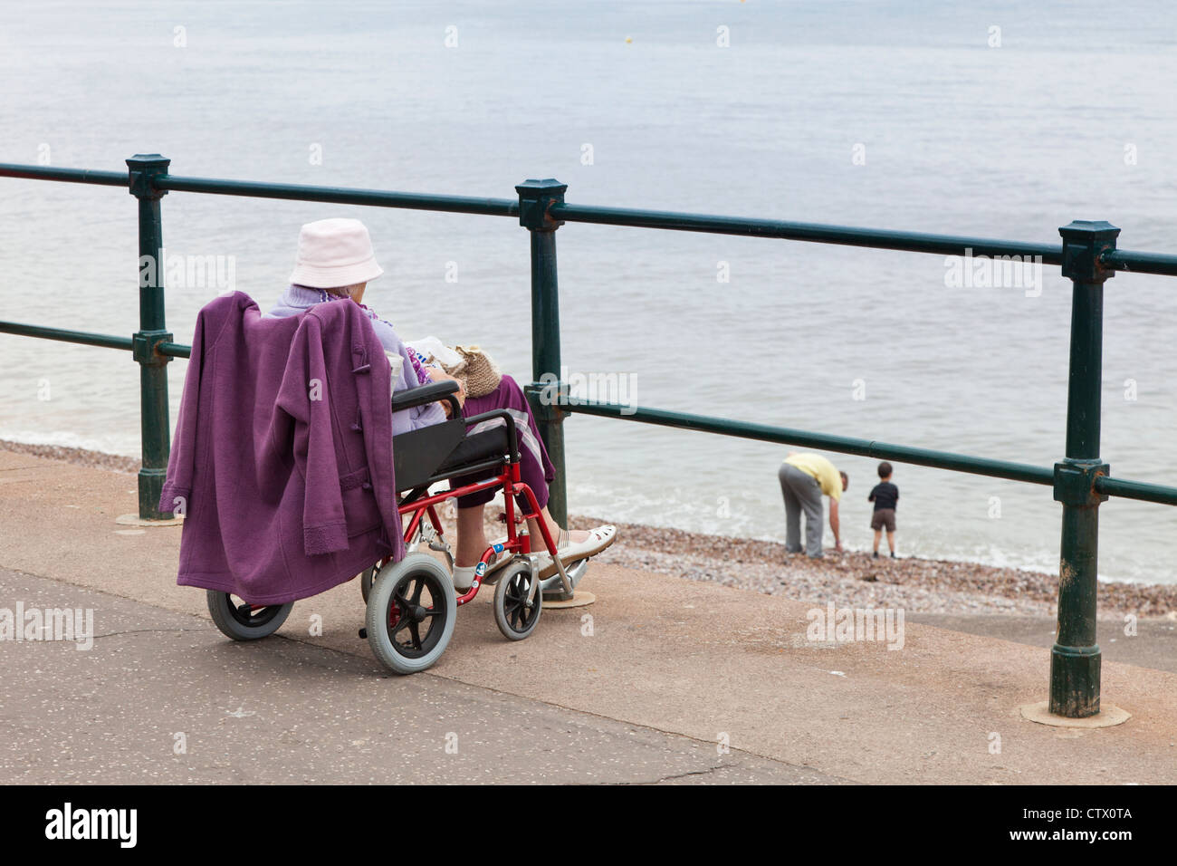 Eine alte Dame im Rollstuhl am Strand von Sidmouth, Devon, UK Stockfoto