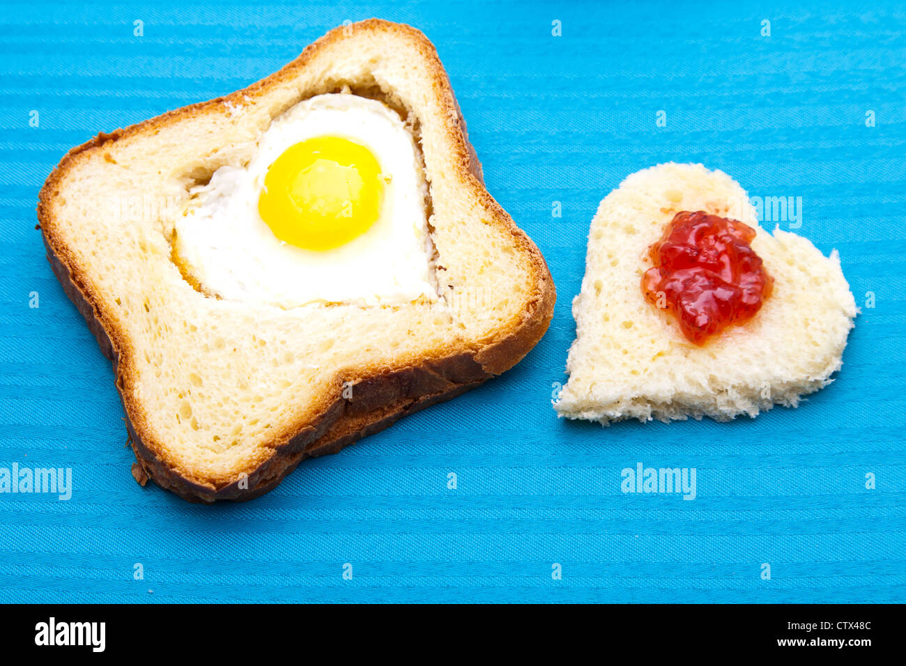 herzförmige Ei und Brot auf blauem Hintergrund Stockfoto