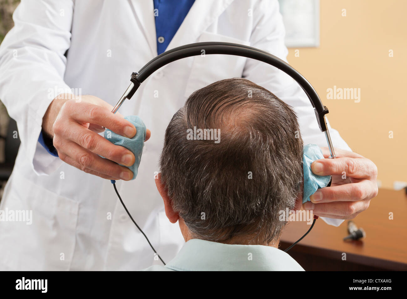 Hörgeräte-Akustiker platzieren einen Kopfhörer an einem Patienten für audiometrische Bewertung Stockfoto
