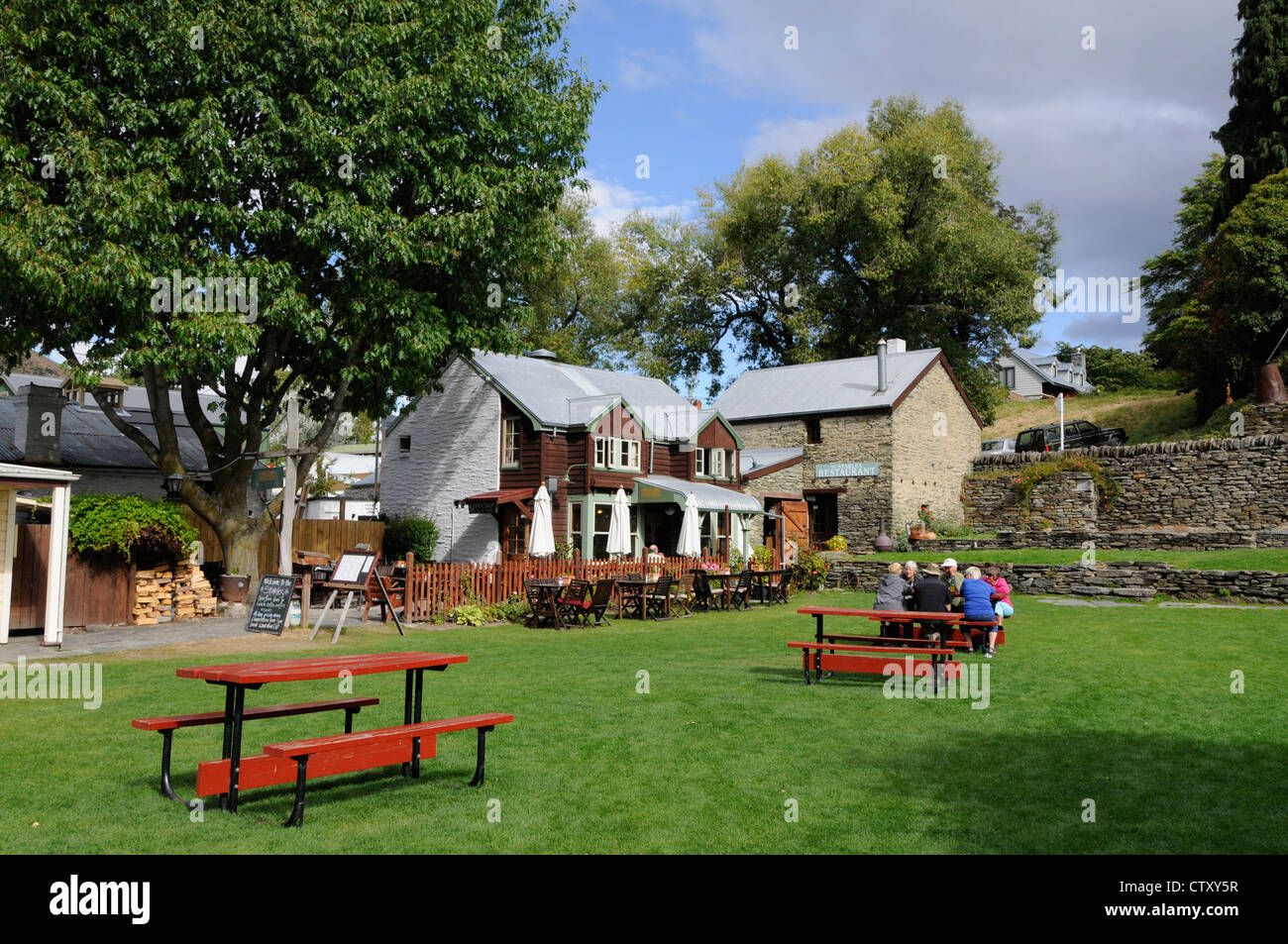 Besucher, die einen Nachmittagstee auf dem Rasen neben einem Teesaal der Buckingham Street genießen, befindet sich die historische Goldgräberstadt Arrowtown in Otago, Neuseeland Stockfoto