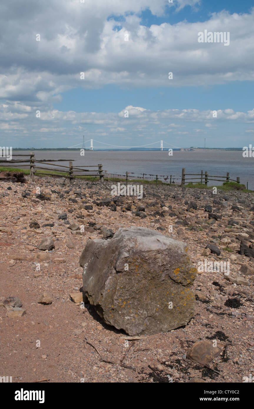 Ufer des Flusses Severn mit Felsen und Kiesstrand und Severn Bridge im Hintergrund Stockfoto