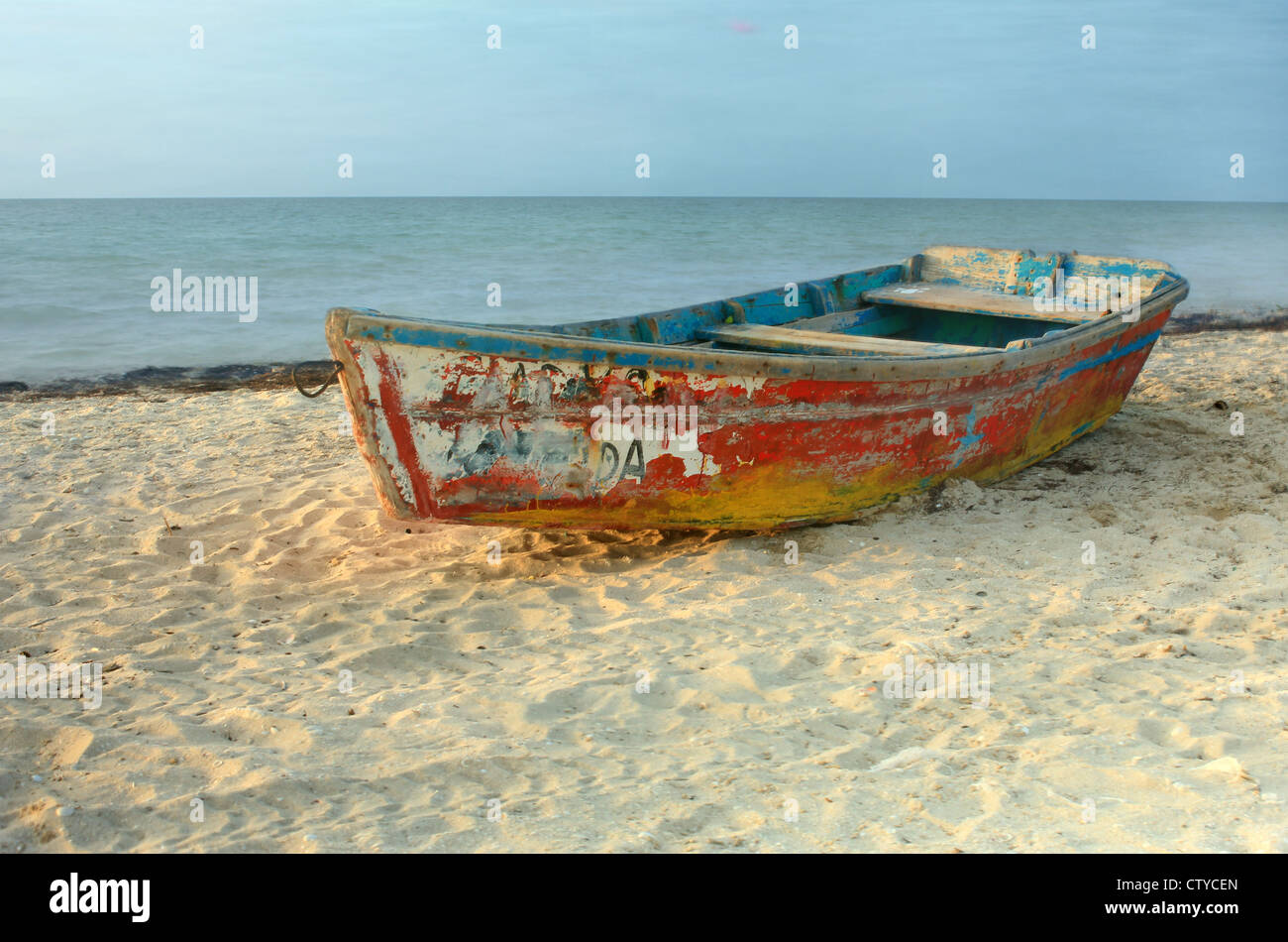 Solo-Ruderboot mit abblätternde Farbe ruht auf Sandstrand in Progreso, Yucatan, Mexiko Stockfoto