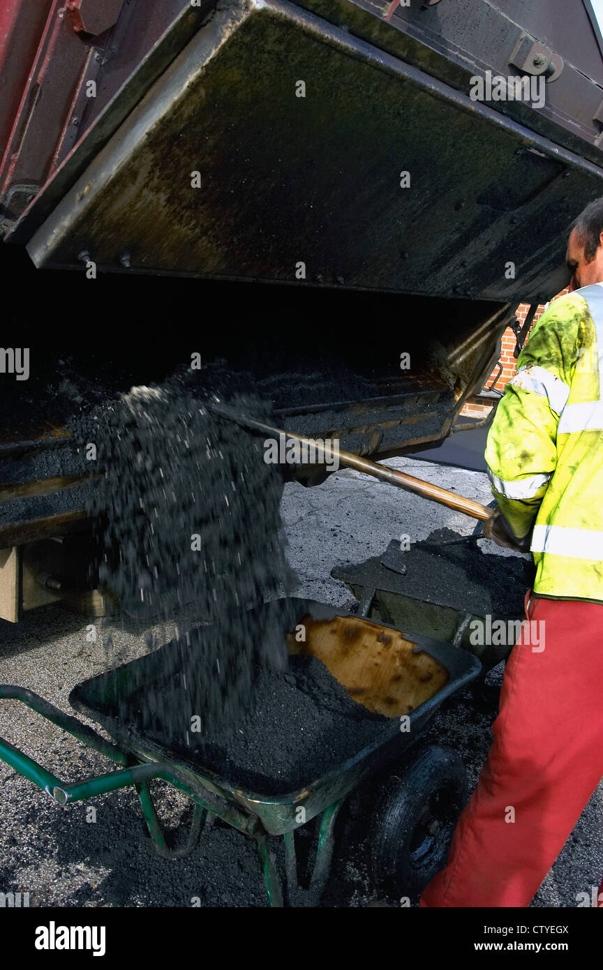 Verbreitung von heißem Asphalt mit Asphalt-Truck und Schubkarre. Stockfoto