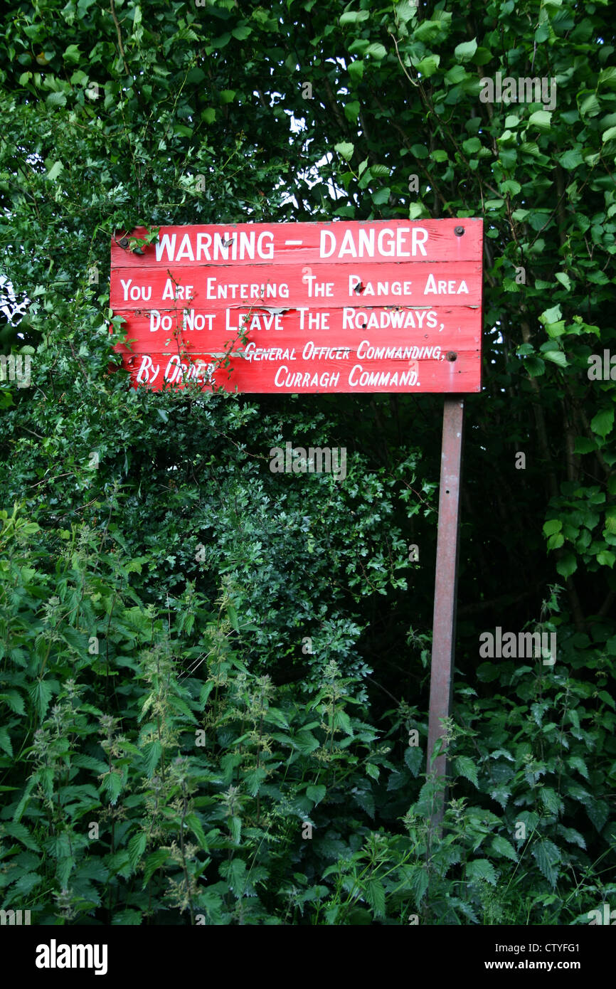 Warnschild Warnung Rot Farbe Board unter den Büschen in den Bergen Wald wo Soldaten Army training live in Irland Wicklow in Europa ist. Stockfoto
