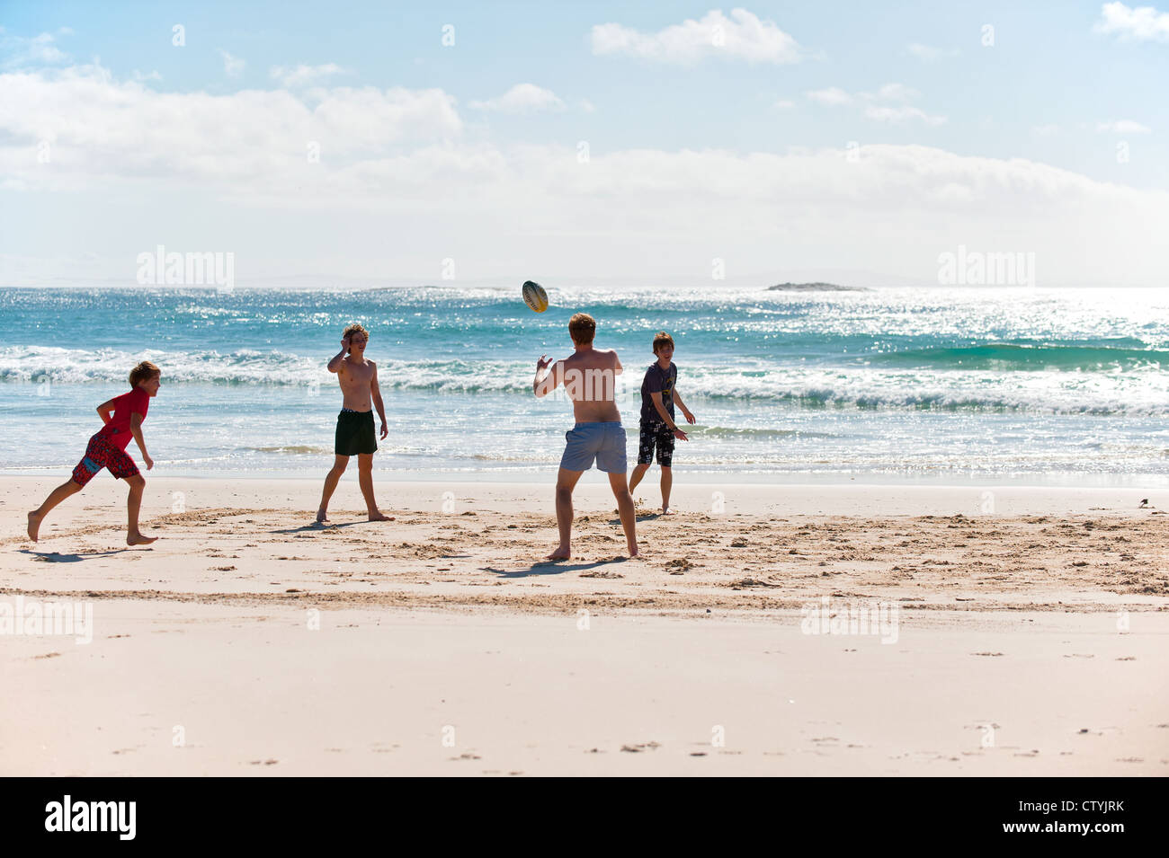 Jungen spielen mit einem Ball auf Zylinder Strand auf North Stradbroke Island in Queensland, Australien. Stockfoto