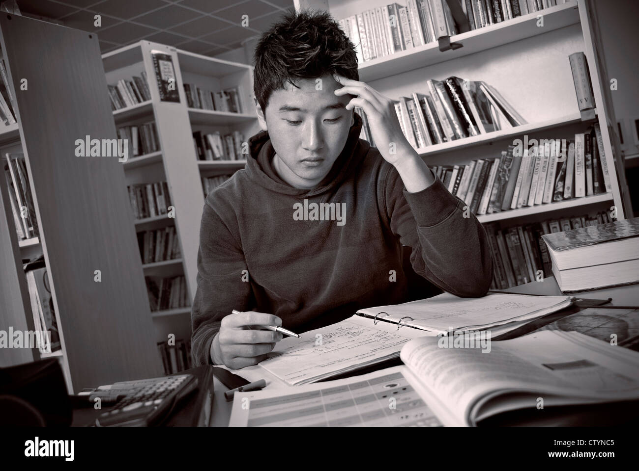 Orientalische Teenager männliche Schüler tief in Gedanken mit seinem Studium in der Schulbibliothek Stockfoto