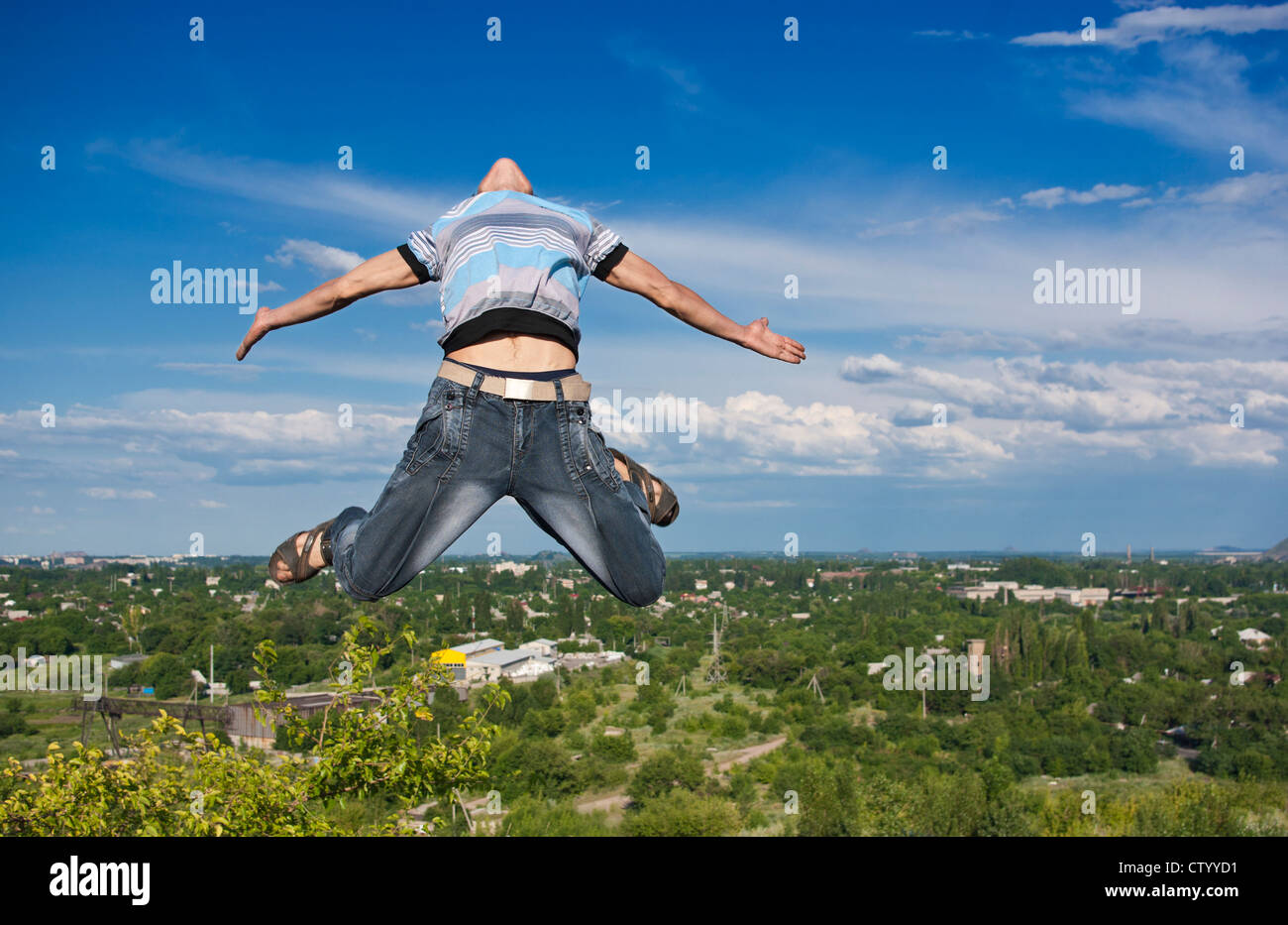 Junge springt vor dem Hintergrund einer Stadt und Himmel Stockfoto