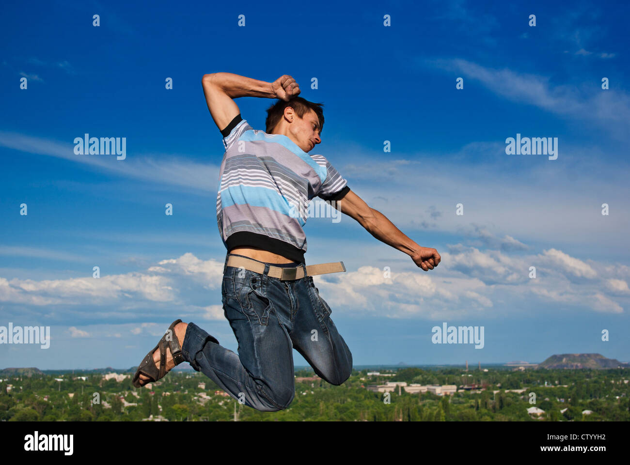 Junge springt vor dem Hintergrund einer Stadt und Himmel Stockfoto