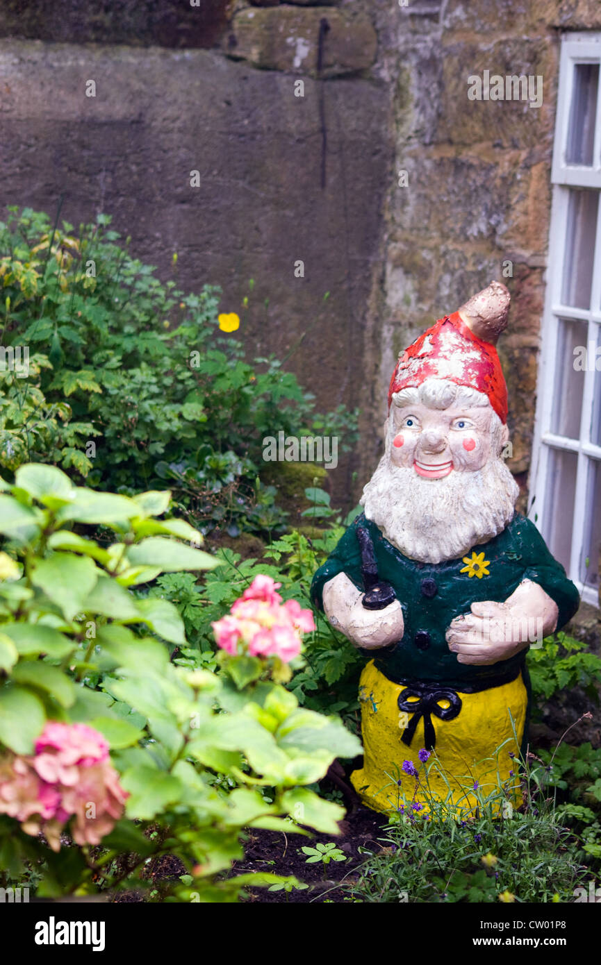 Bunte GARTEN GNOME UNTER PFLANZEN IN EINEM GARTEN ROBIN HOOD'S BAY Stockfoto