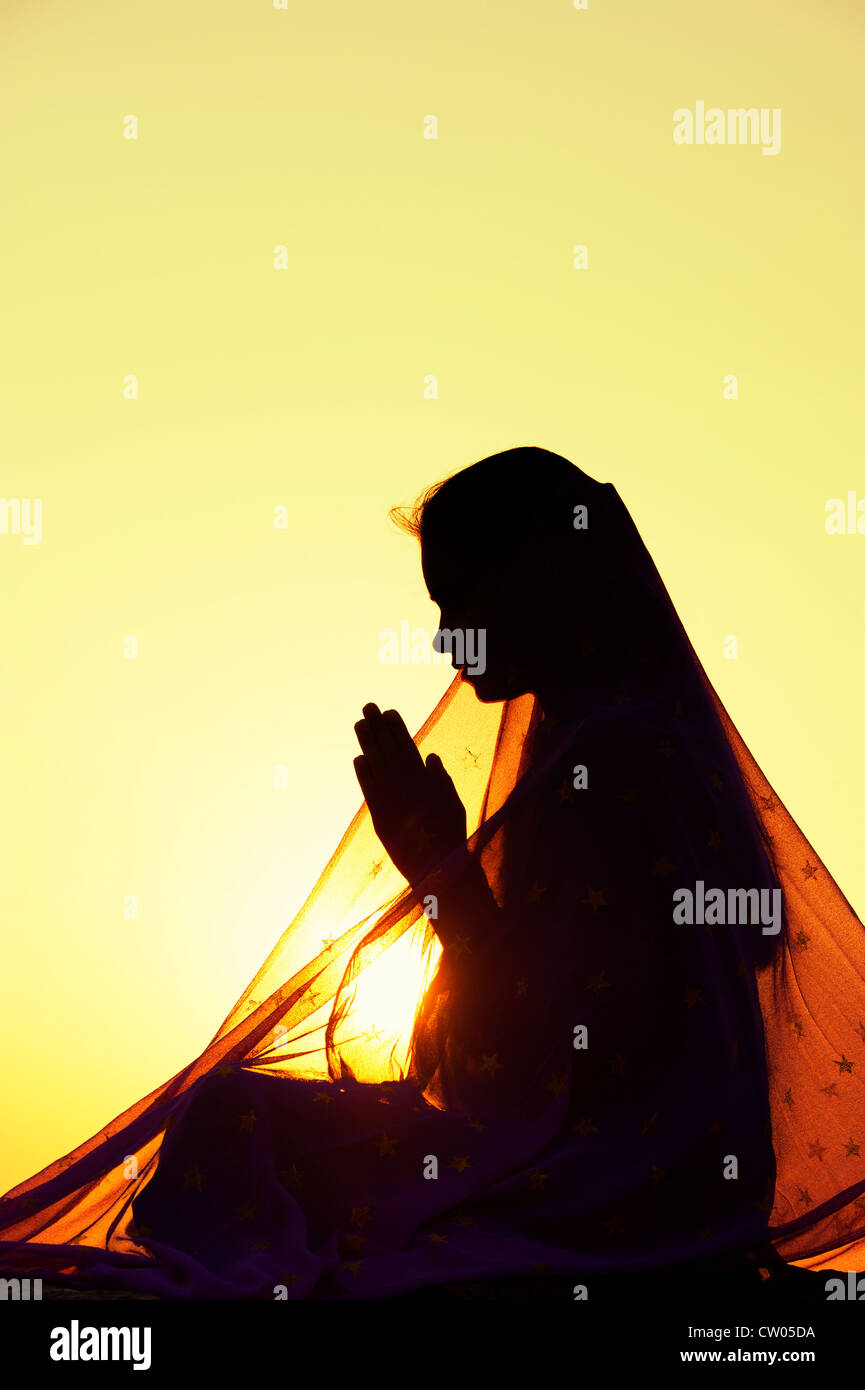 Indische Teenager-Mädchen beten bei Sonnenuntergang mit einem Stern Schleier bedeckt. Silhouette. Indien Stockfoto