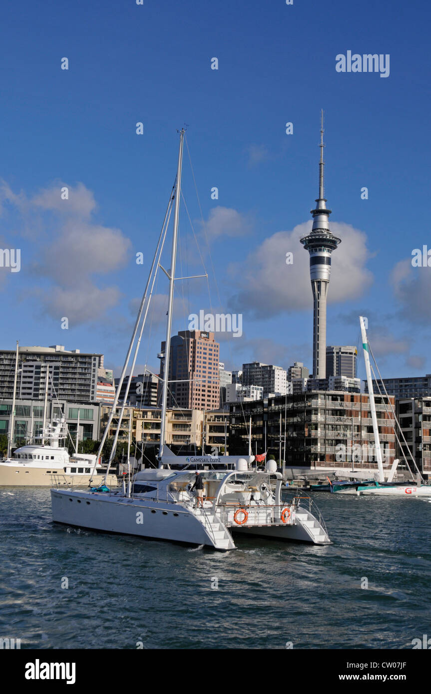 60 ft Motorsegler Katamaran Te Okupu, Segeln in Viaduct Harbour in Auckland und der Sky Tower in Neuseeland Stockfoto