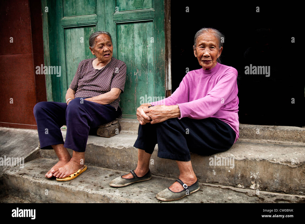 Ältere chinesische Frauen sitzen vor ihrem Haus Stockfoto