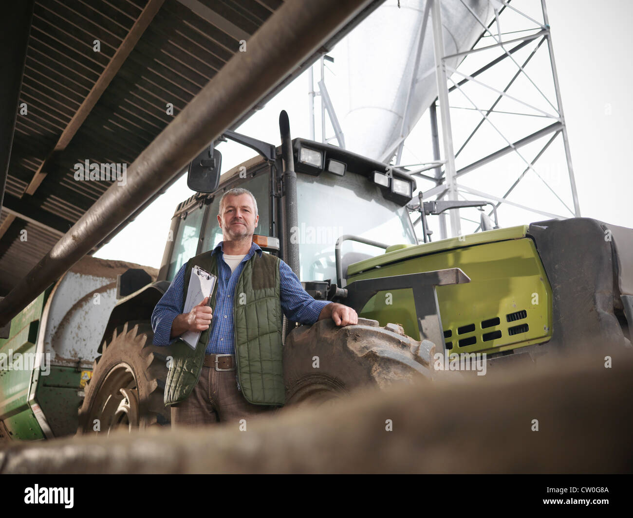 Landwirt Holding Zwischenablage mit einem Traktor Stockfoto