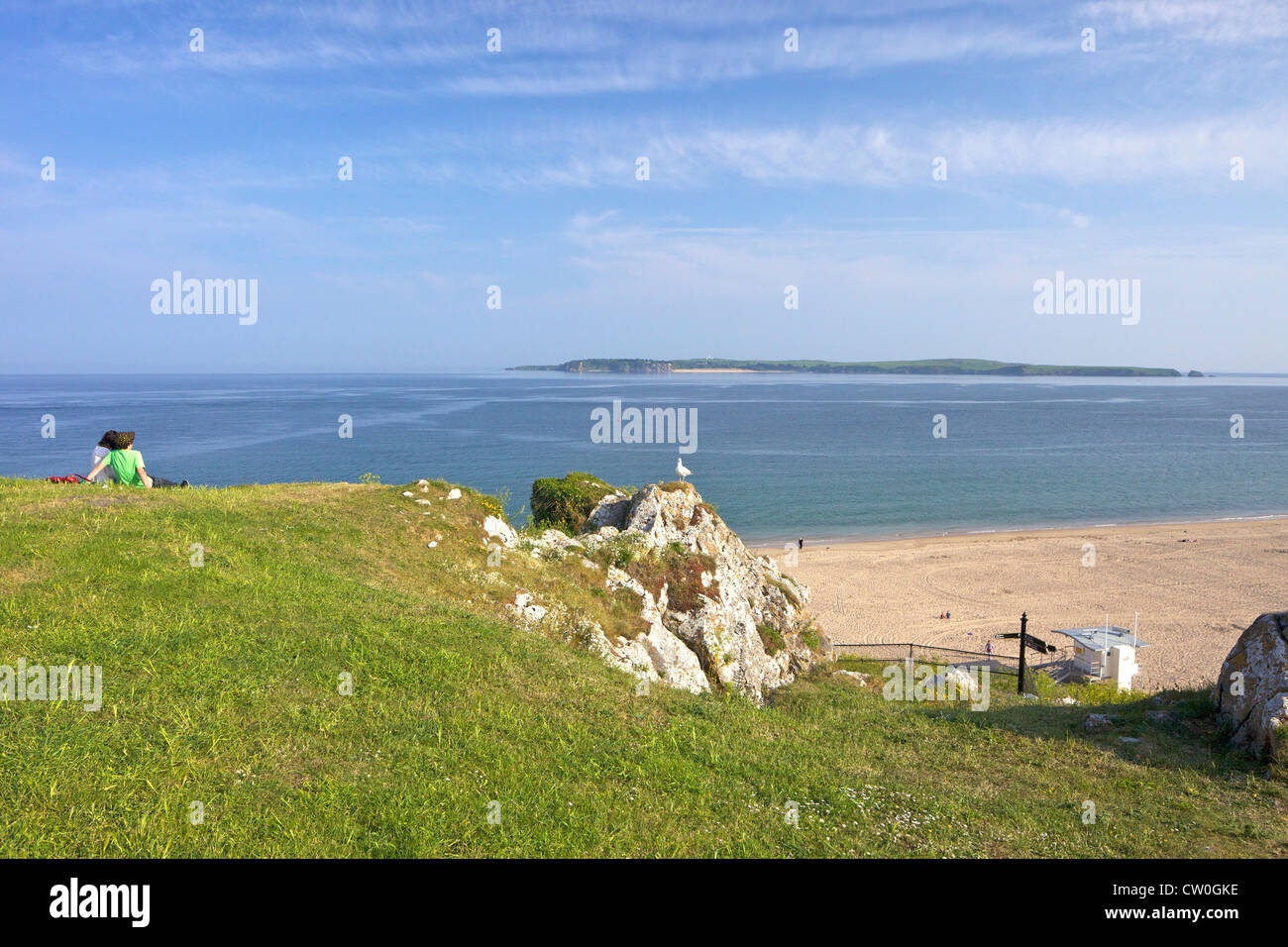 Zwei Jugendliche auf der Suche nach Caldey Island und South Beach im Sommer Sonnenschein, Tenby Pembrokeshire Nationalpark, Wales Stockfoto