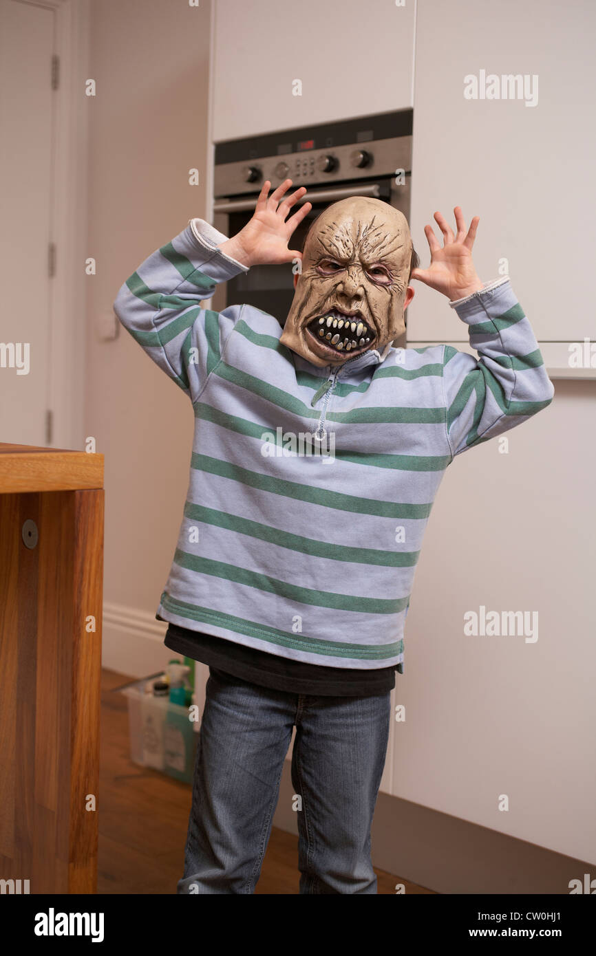 Junge mit Halloweenmaske in Küche Stockfoto