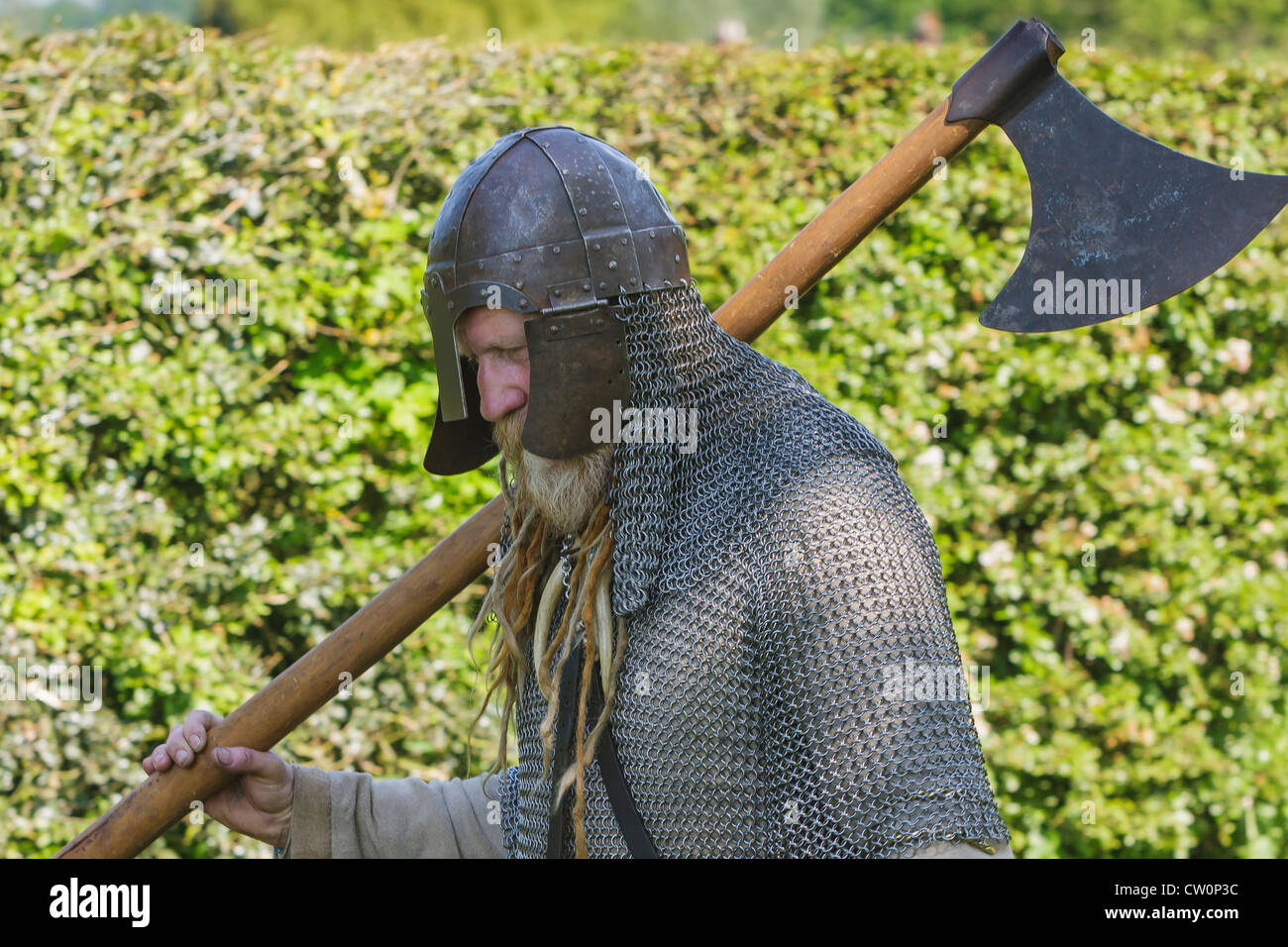 Mann in frühen mittelalterlichen Kettenhemd und Helm trägt ein Krieg Axt während Anglo-Saxon und Viking Reenactment. St Albans, UK. Mai 2012 Stockfoto