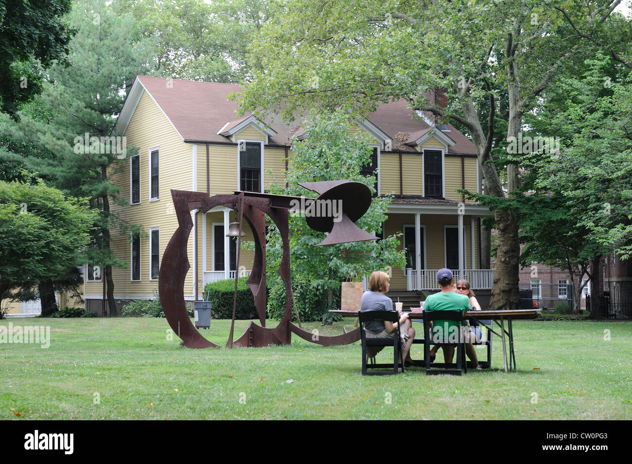 Häuser früher besetzt von Militärpersonal auf Governors Island Form eine Kulisse von Mark di Suveros Bildhauerei. Stockfoto