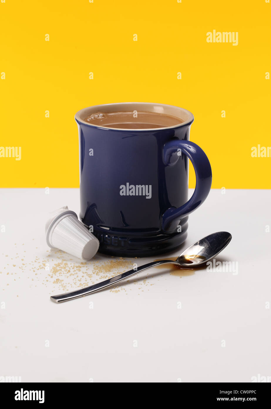 Eine Kaffeetasse mit einem Löffel, Kaffee Flüssigkeit, Creamer Paket und losen Zucker. Stockfoto