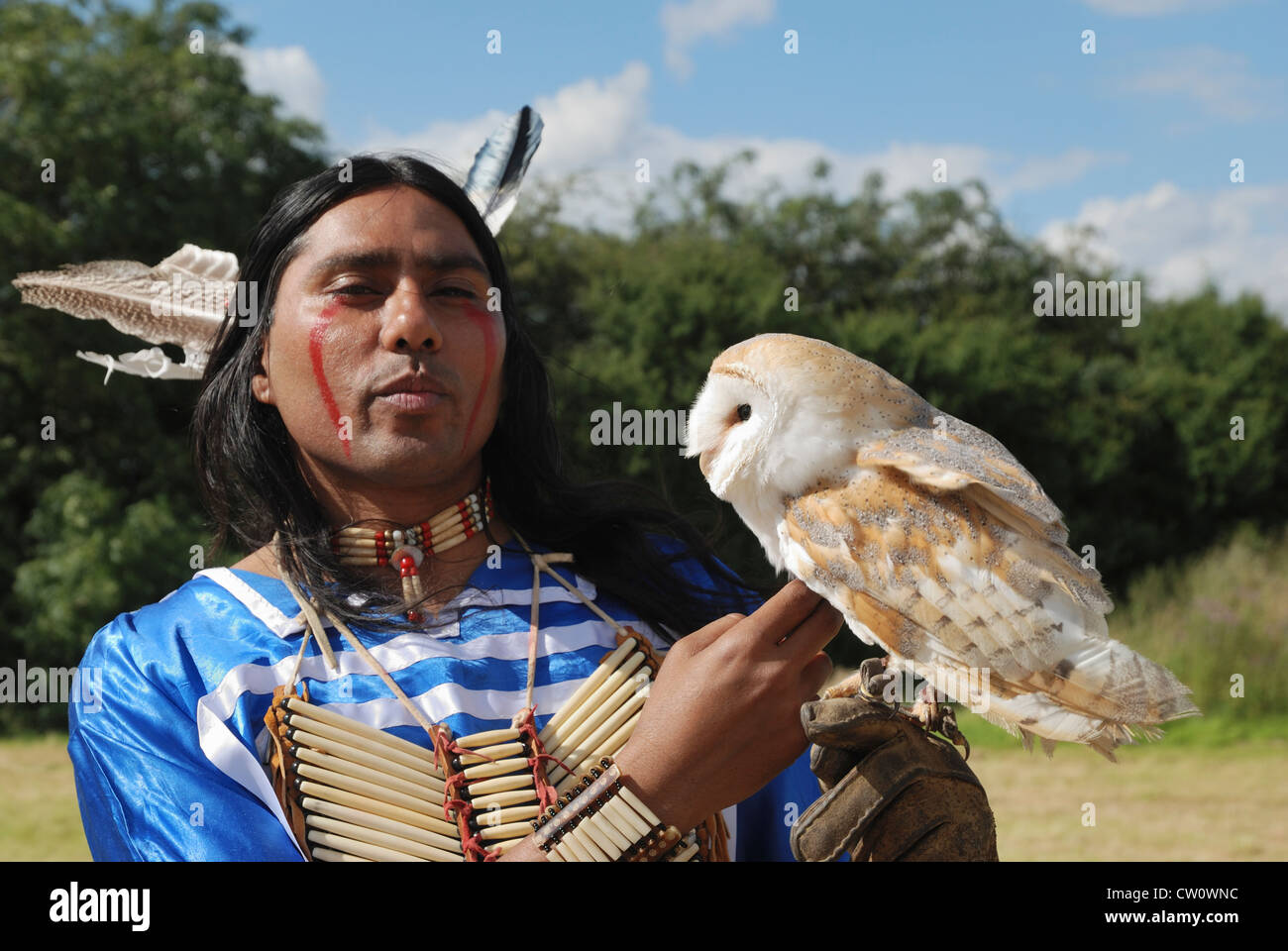 Ein Mann posiert im traditionellen Kleid Lakota (Sioux) mit einer Schleiereule. Stockfoto