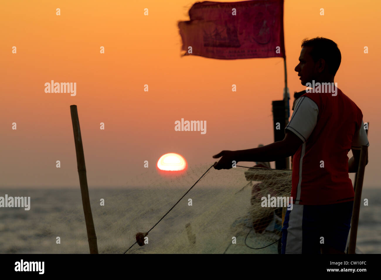 Fischer zieht in sein Netz auf Mandrem Beach, Goa bei Sonnenuntergang Stockfoto