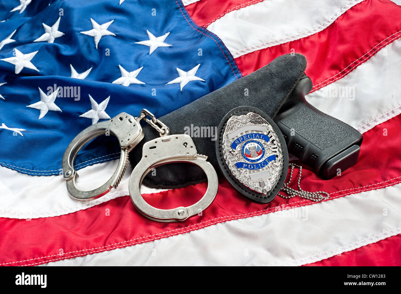 Polizei Abzeichen, Pistole und Handschellen an eine amerikanische Flagge als Symbol für Gesetzdurchführung in den Vereinigten Staaten. Stockfoto