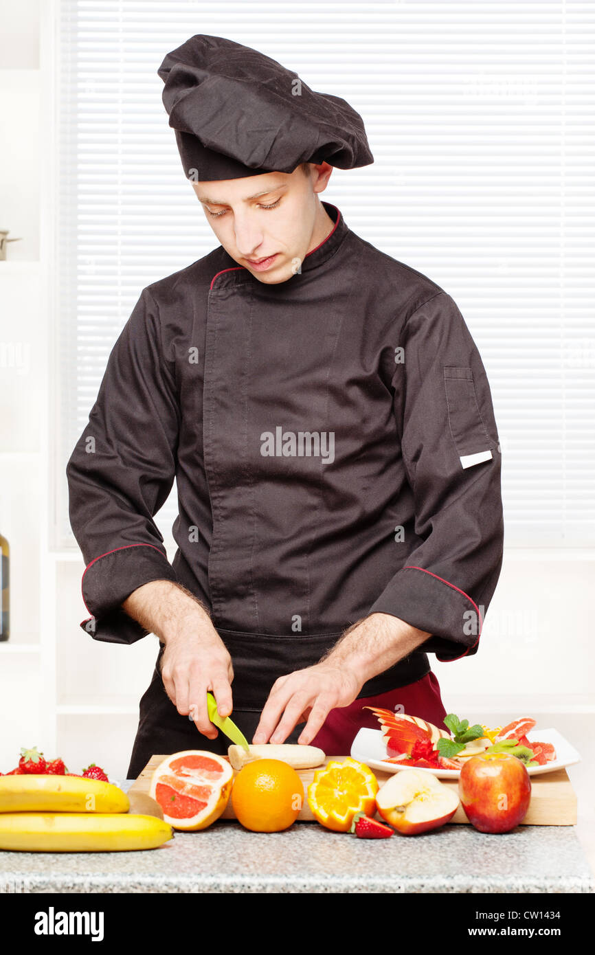 Koch in schwarzen einheitlichen Schnitt Obst an Bord in Küche Stockfoto