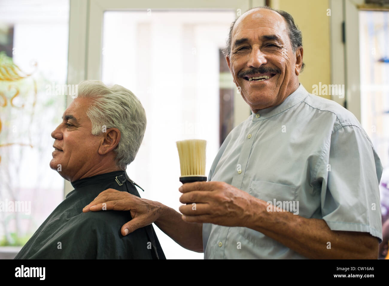 Alten Friseur hält Pinsel für Hagin und lächelnd zu Kamera in alte Mode-Friseur Stockfoto