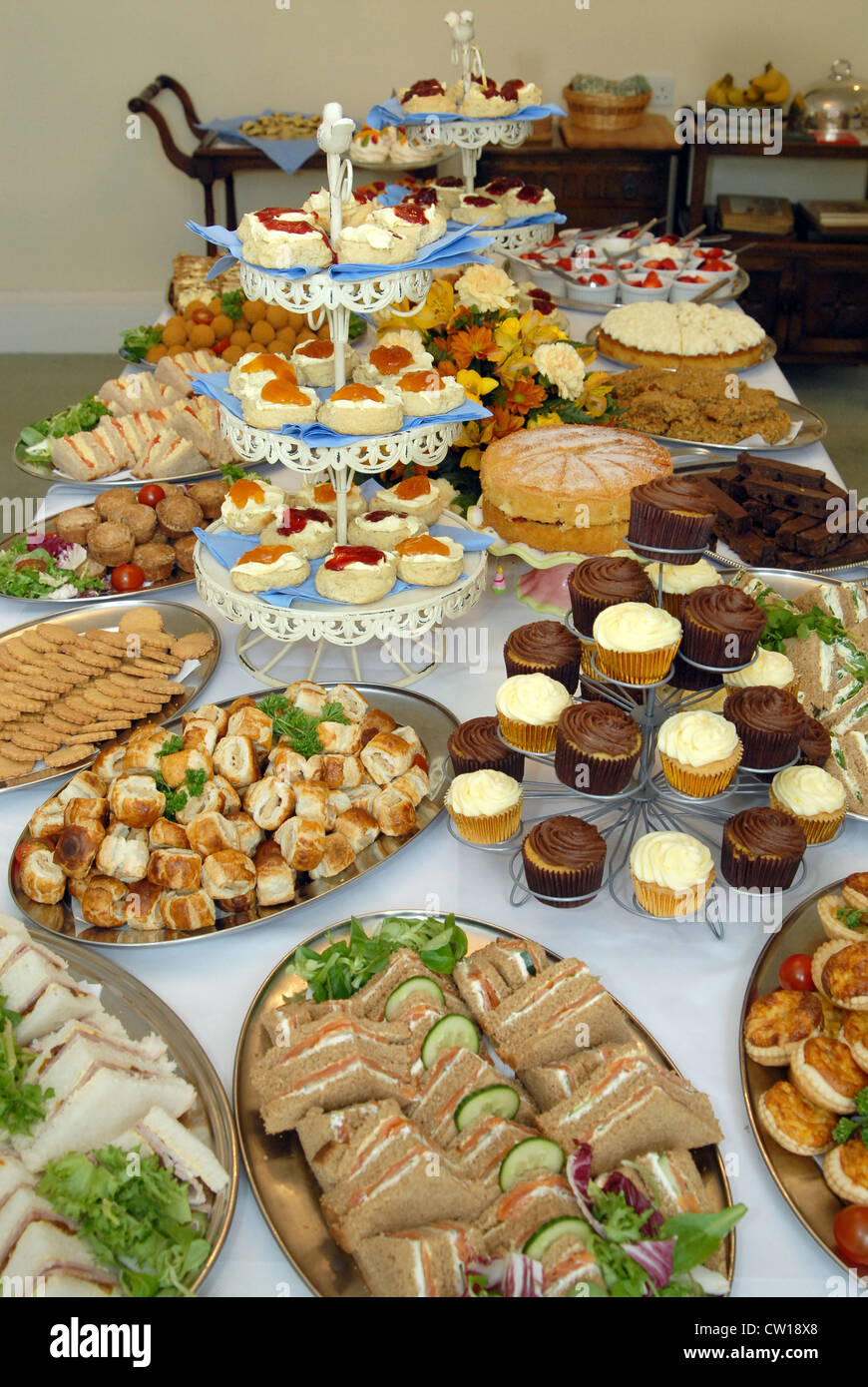 Kuchen, geräucherter Lachs Sandwiches, Scones (mit Marmelade & Clotted Cream), Schweinefleischpasteten und Muffins auf dem Büfett auf einer Party. Stockfoto
