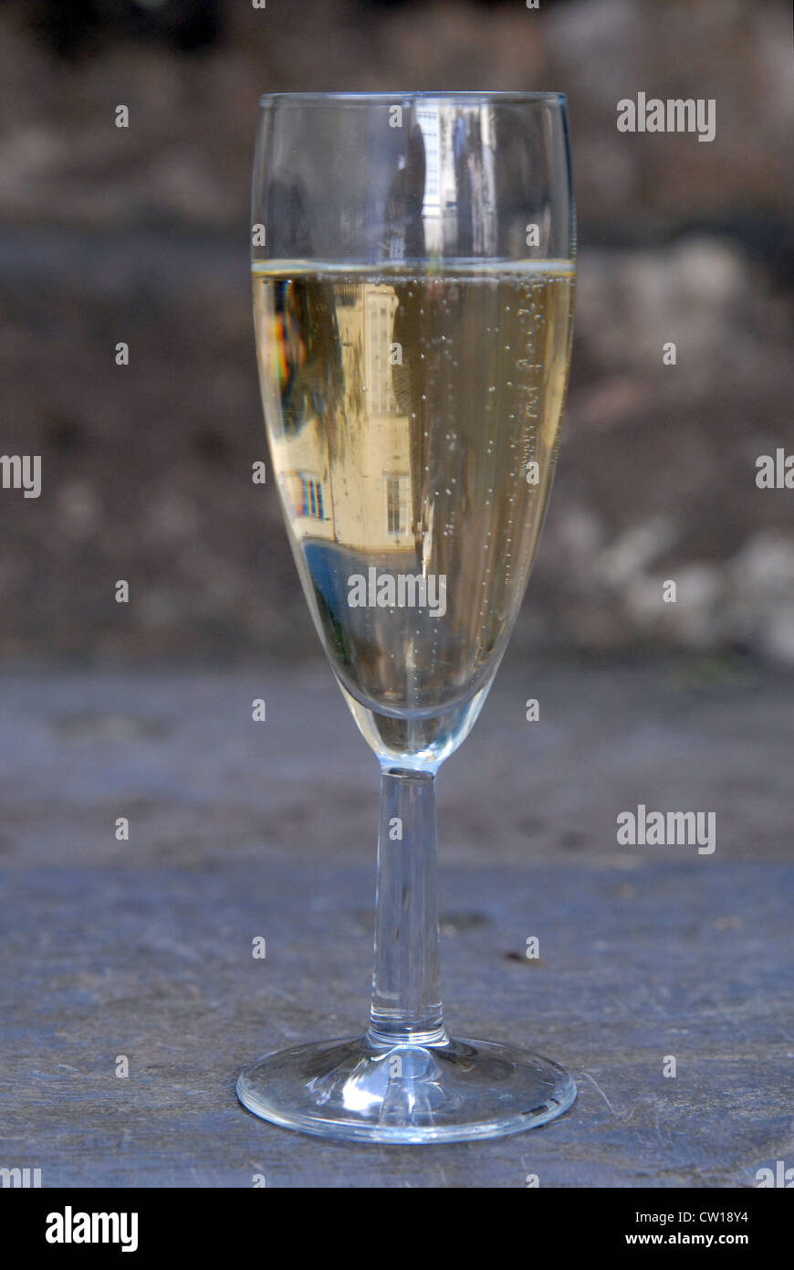 Ein Glas Champagner auf einen Garten Schritt bei einer goldenen Hochzeitsfeier.  Ein Haus spiegelt sich im Glas. Stockfoto