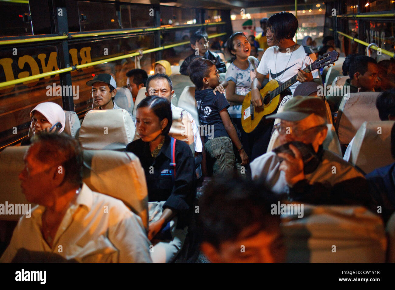 Straßenmusikanten (Ngamen) spielen Musik in einem öffentlichen Bus in der Nacht in Surabaya, Indonesien. Stockfoto