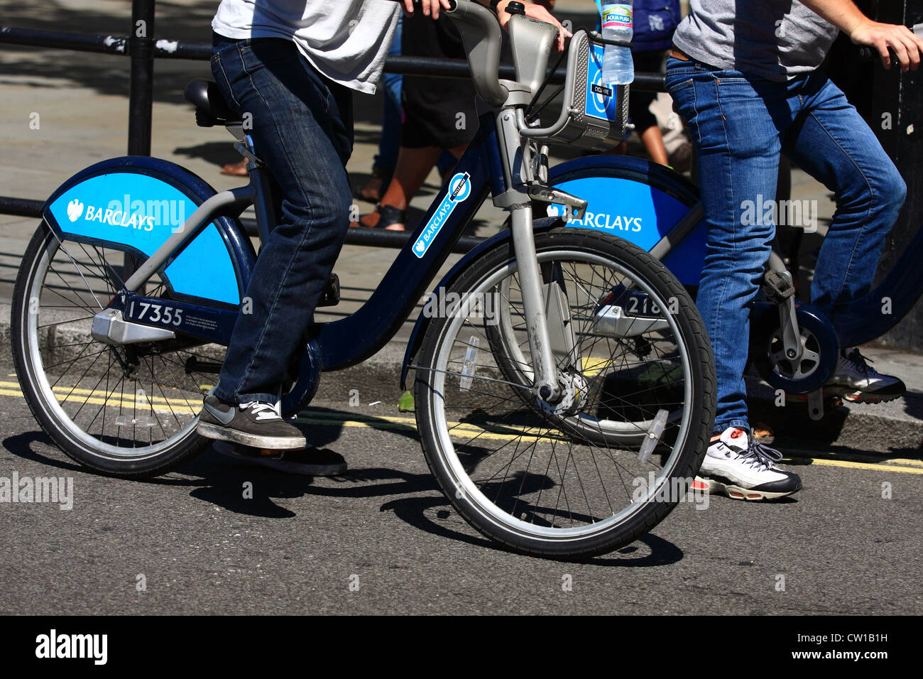 Zwei Boris Bikes und Fahrer warten auf einer Straße in London Stockfoto