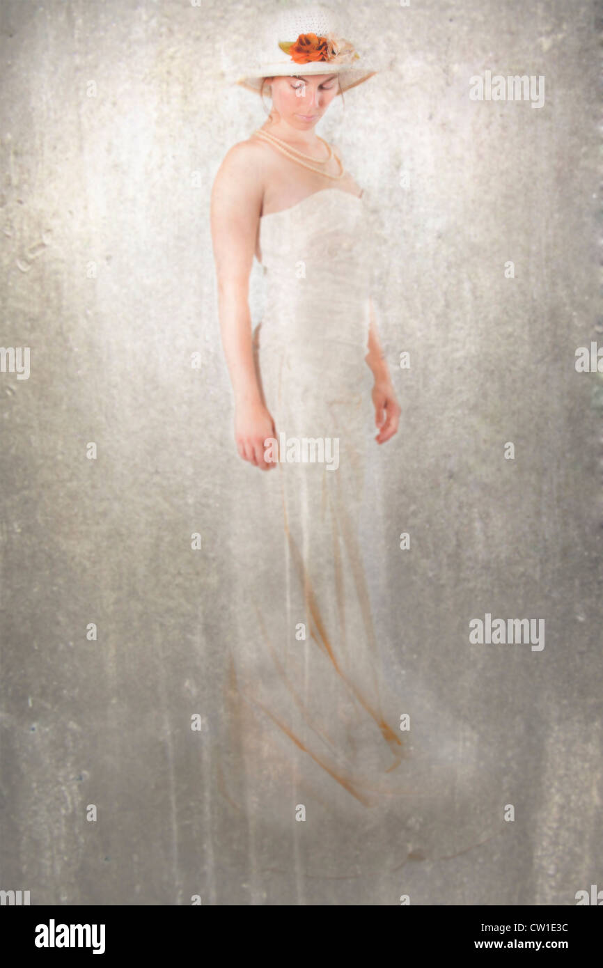 eine Frau in einem weißen Kleid mit einem Strohhut Stockfoto