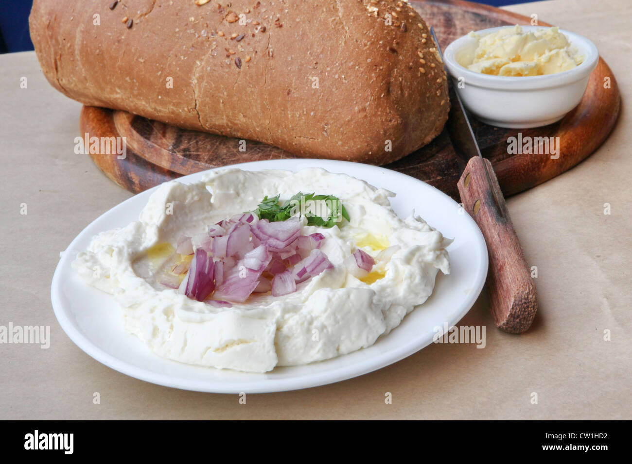 Labneh (libanesische Joghurt Käse aus Kuhmilch hergestellt) mit Olivenöl, Zwiebeln und Brot und Butter serviert Stockfoto