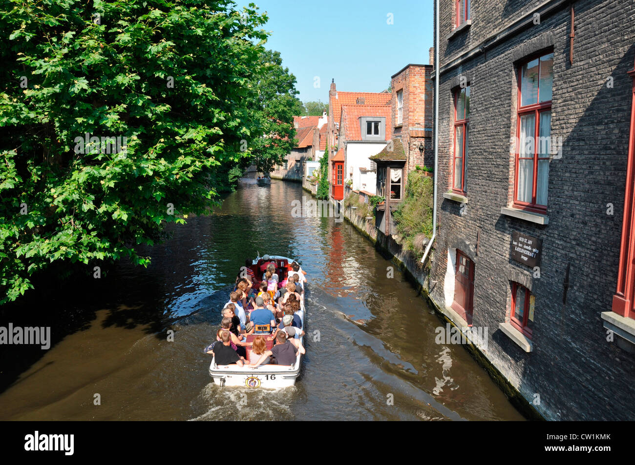 An einem heißen Tag im Sommer, wenn das Boot in voller Touristen langsam ihren Weg entlang einer Brügge Kanal. Belgien, Europa. Stockfoto