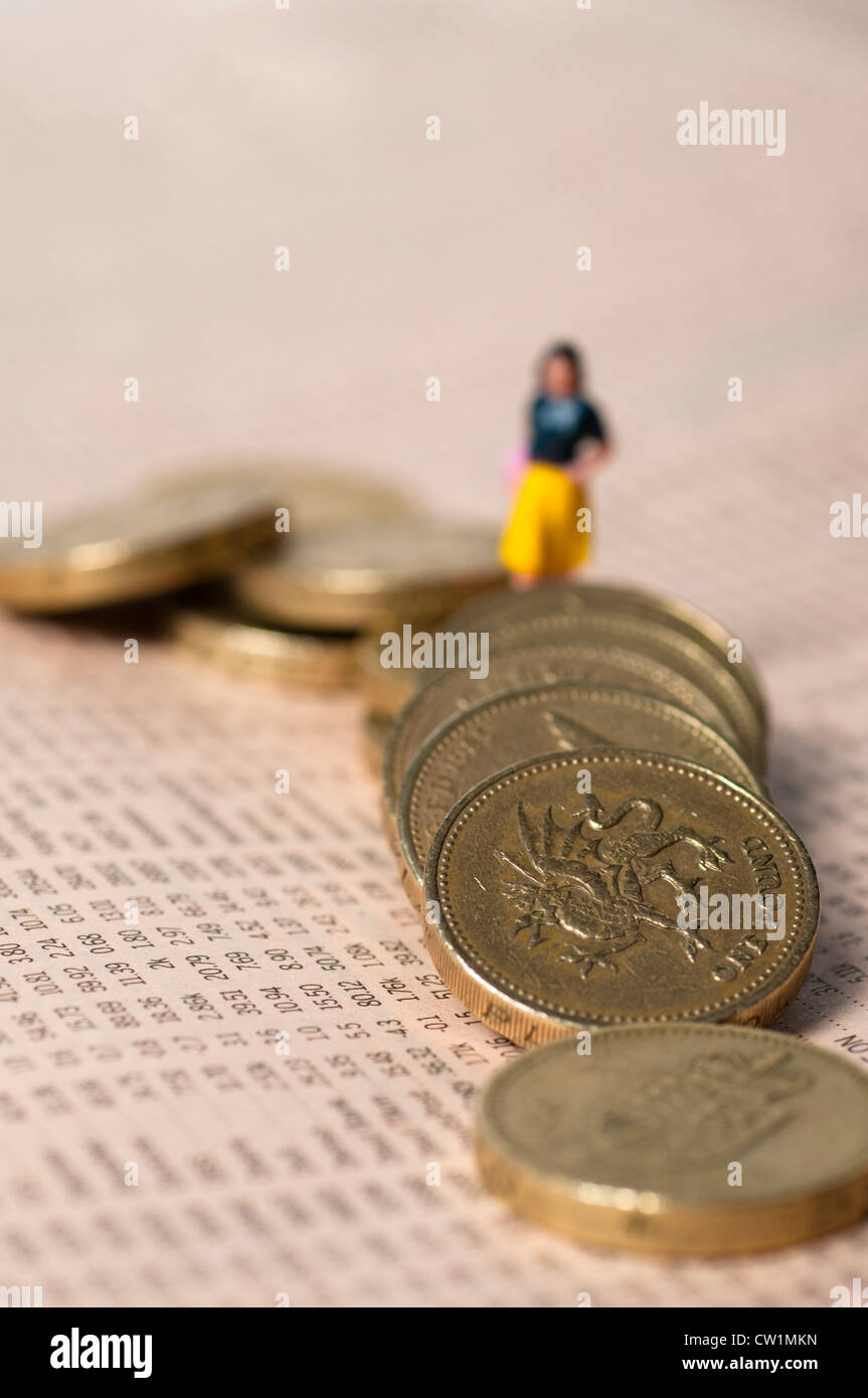 Kleine Figur einer Frau fiel ein Pfund Münzen Überklettern legte hinüber zur Aktie Stockfoto