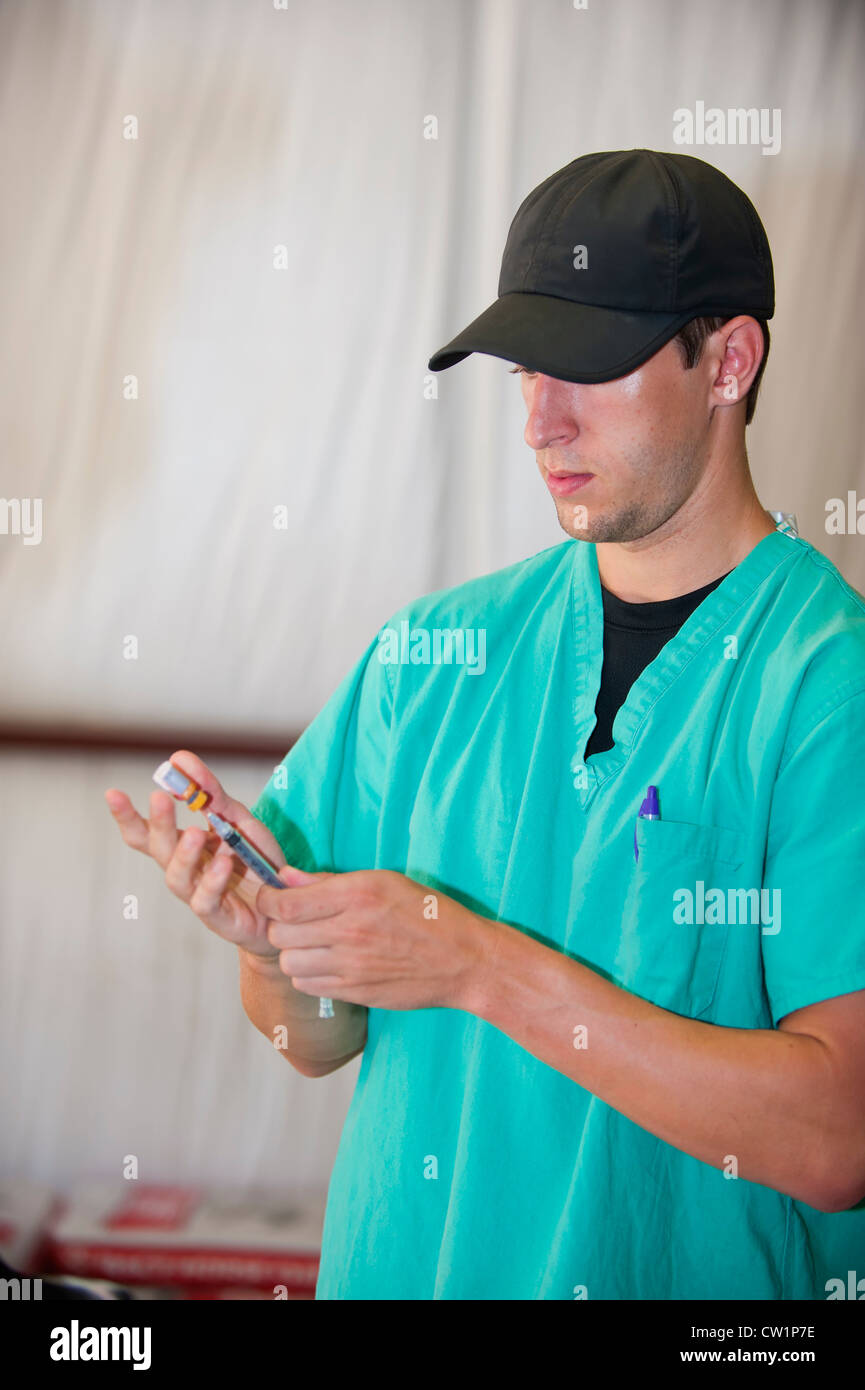 Jungen männlichen Arzt Assistentin Füllung Spritze in einem provisorischen Zelt-Klinik Stockfoto